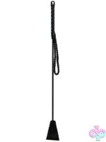 Rouge PVC riding crop in black and red on a dark surface showing wrist loop and flexible shaft